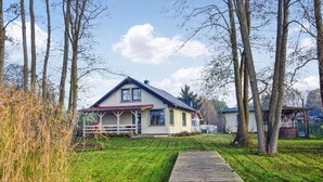 Een huis met een veranda, een gazon en bomen.