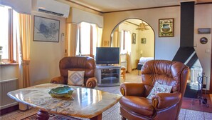 A living room with leather armchairs, a glass coffee table, a flat-screen TV, and a fireplace. - Stunning home in Svängsta with sauna (Svängsta)