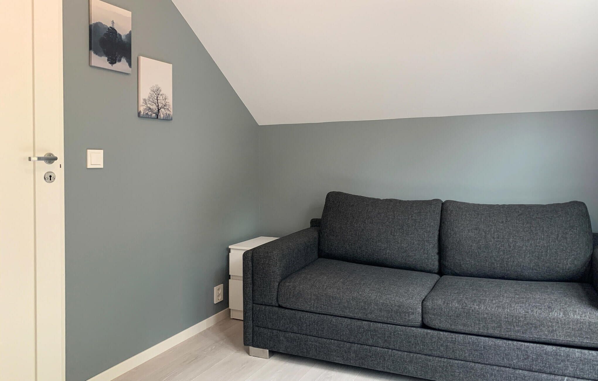 Une pièce avec un canapé gris, une table d’appoint blanche et une porte dotée d’un trou de serrure.