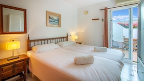 A double bed with a wooden headboard, a bedside lamp, and a painting on the wall.