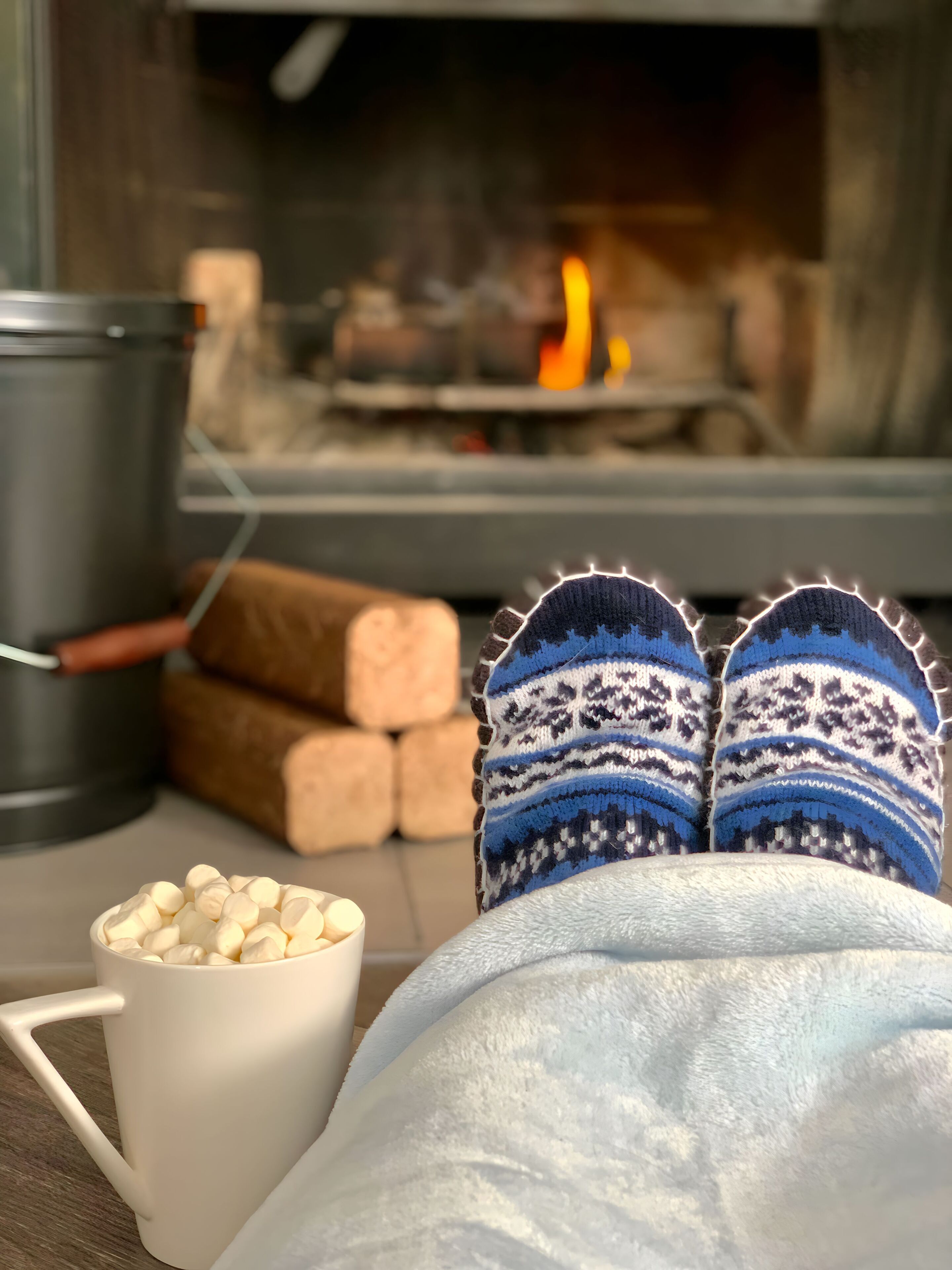 A cozy room with a fireplace, a white mug, and a pair of patterned slippers.