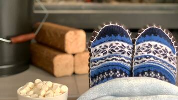 A cozy room with a fireplace, a white mug, and a pair of patterned slippers.
