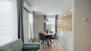 Un salon moderne comprenant un canapé, une table à manger avec des chaises et un coin cuisine avec un évier et un plan de travail.