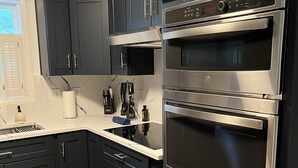 A modern kitchen with dark cabinetry, a stainless steel oven, and a marble backsplash. - New modern kitchen in great location to RDU and RTP (Morrisville)