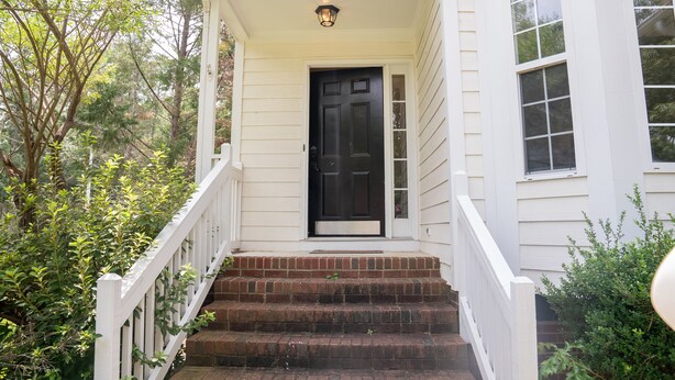 A white house with a black front door, a small porch, and a brick staircase. - New modern kitchen in great location to RDU and RTP (Morrisville)