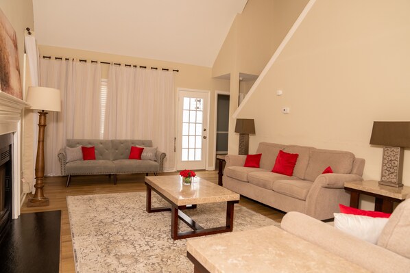 A living room with a fireplace, two sofas, a coffee table, and a staircase.