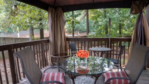 A covered outdoor patio with a round glass table, two chairs, and a vase of flowers. - New modern kitchen in great location to RDU and RTP (Morrisville)