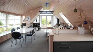 Un loft moderno con comedor, cocina y un amplio ventanal que ofrece vistas a zonas verdes.