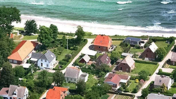 Una zona residencial costera con casas, una playa y una vista despejada del océano.