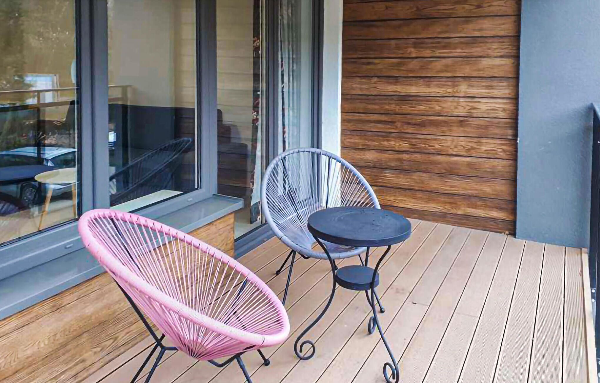 Eine Holzterrasse mit zwei Stühlen und einem Tisch.