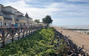 A coastal promenade with a wooden walkway, beach, and a row of buildings with visible signage. - 1 bedroom cozy apartment in Mielno (Mielno)