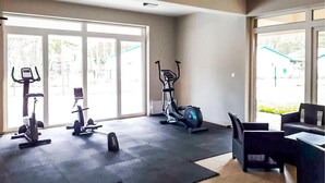 Een sportschool met trainingsapparatuur, grote ramen en een zithoek.