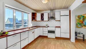 Eine moderne Küche mit weißen Schränken, einer Holzarbeitsplatte und einem großen Fenster.