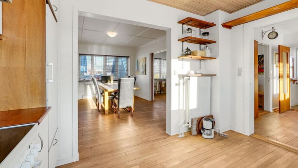 Eine moderne Küche mit Holzboden, weißen Schränken und einer integrierten Kaffeemaschine.