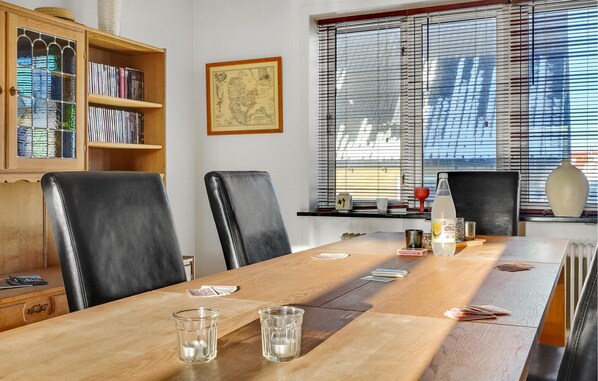 A conference room with a wooden table, black leather chairs, a bookshelf, and a window with blinds. - Lovely home in Thyborøn with kitchen (Thyborøn)