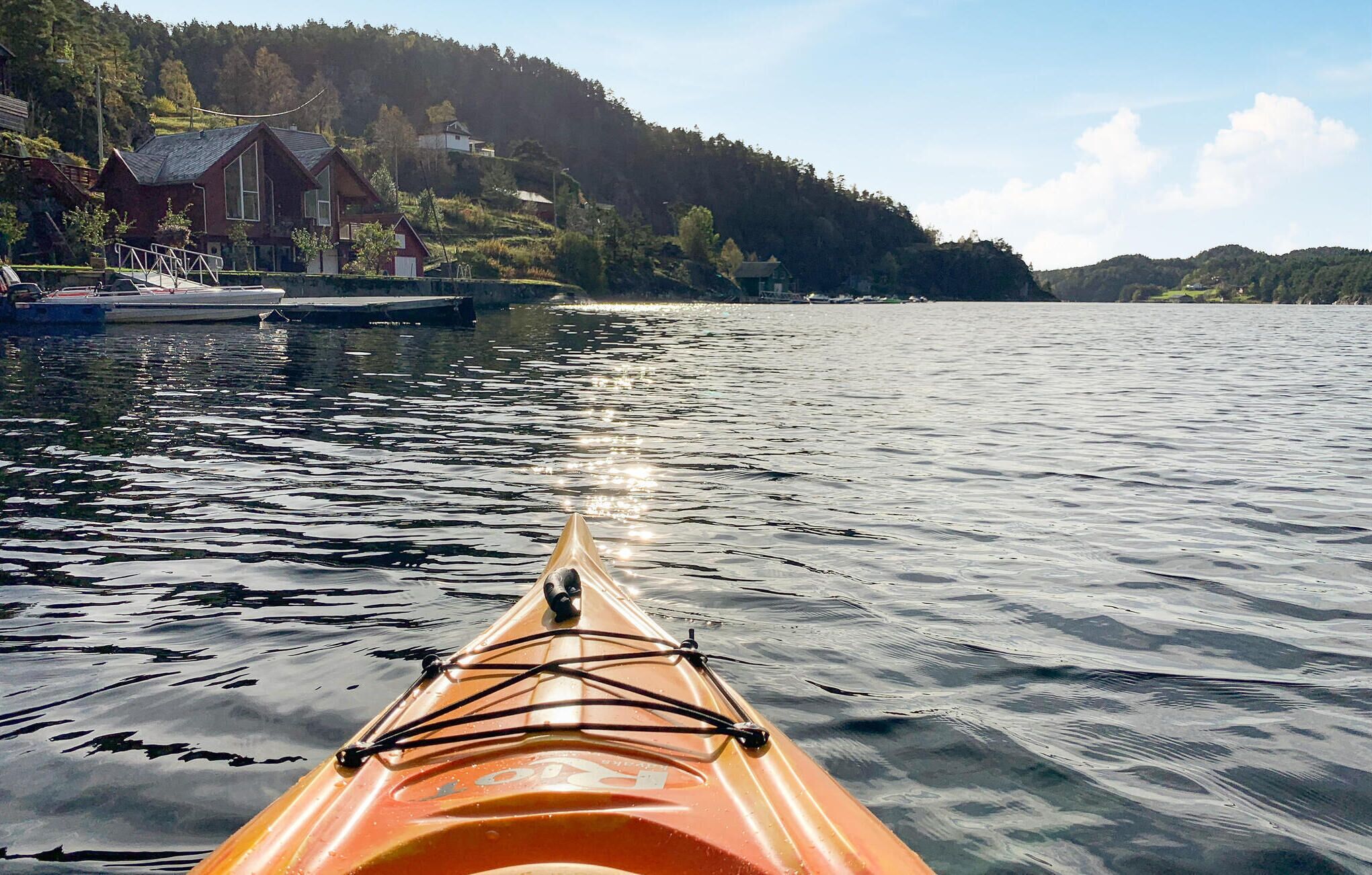 A kayak on calm water with a forested hill in the background.