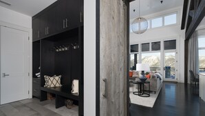 Ein modernes Interieur mit einem dunkelholznen Schrank, einer Bank mit Kissen und Blick auf eine gebirgige Landschaft durch große Fenster.