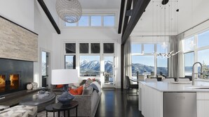 Ein modernes Wohnzimmer mit Kamin, einer Couch und einem Essbereich mit Blick auf Berge.