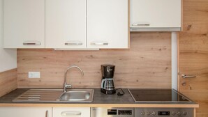 A modern kitchen with white cabinets, a stainless steel sink, a Bosch coffee maker, and an induction cooktop.