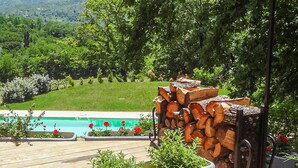 A pool area with a wooden deck, surrounded by lush greenery and a view of a hilly landscape. - 1 bedroom nice home in Dieulefit (Dieulefit)