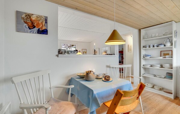 Enjoy meals in this cozy dining area with a table set for two, featuring a bookshelf and a comfortable chair.