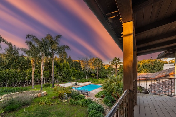 A pool area with a view of the surrounding landscape, including trees and a building in the background.