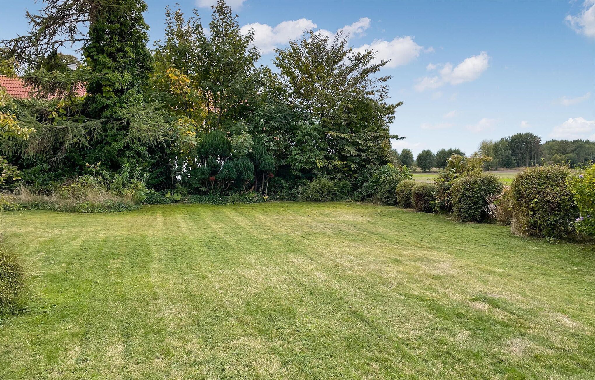 A well-maintained grassy area with dense trees and shrubs in the background.
