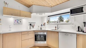 Une cuisine moderne avec des meubles en bois, des appareils électroménagers en acier inoxydable et une fenêtre donnant sur les arbres.