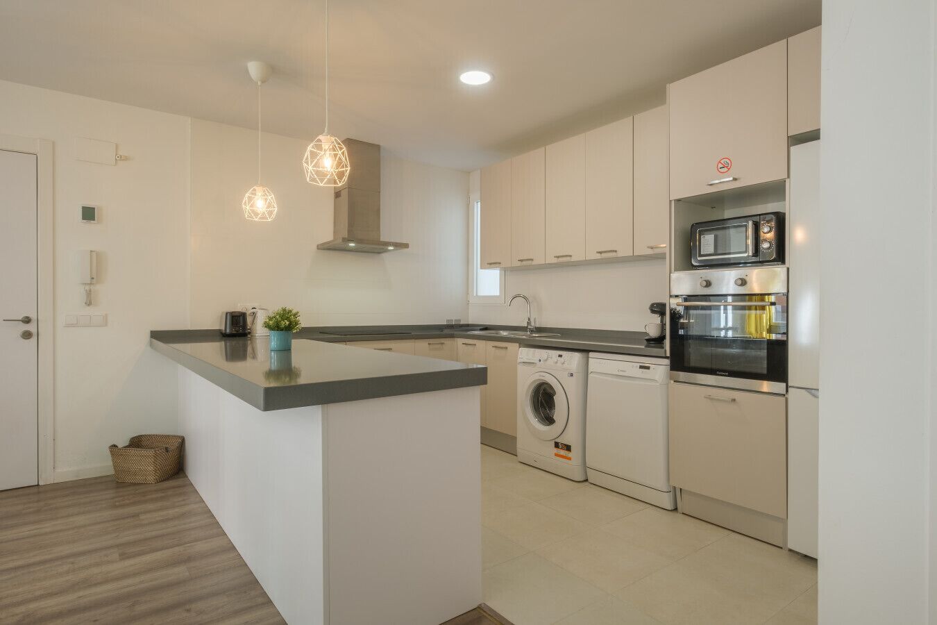 A modern kitchen with a central island, built-in appliances, and pendant lighting.