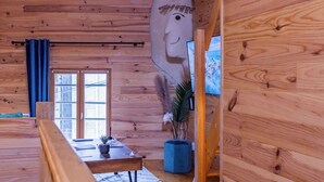 Een houten blokhut interieur met een groot stenen gezichtsbeeldhouwwerk, een eethoek en een televisie.
