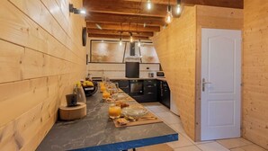 Een compacte keuken met houten wanden, een marmeren werkblad en hangende lampen.