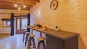 Een houten interieur met een keukenblad, krukken en een klok aan de muur.