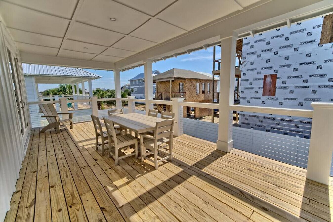 A wooden deck with a table and chairs, overlooking a construction site.