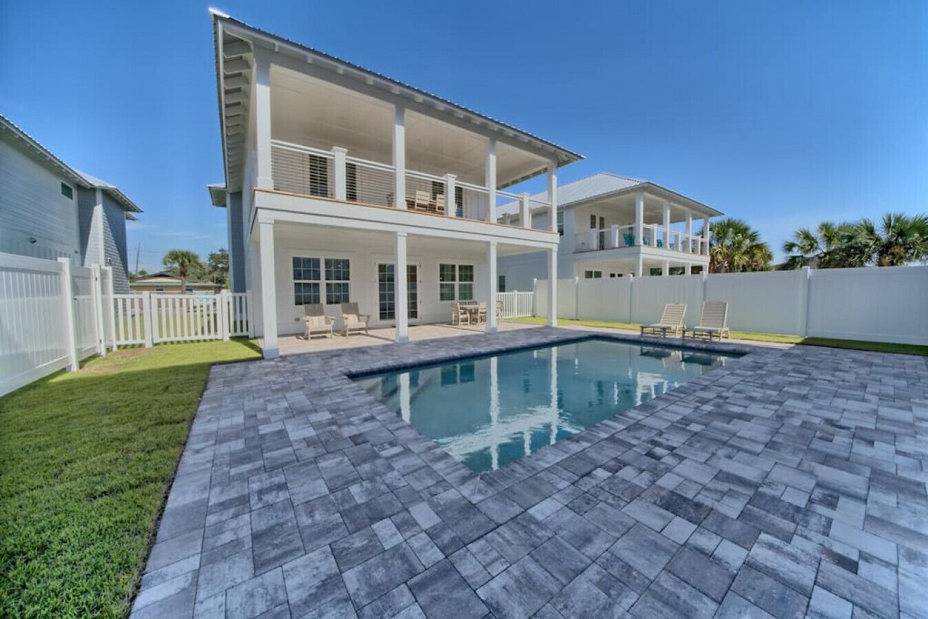 Ein zweistöckiges Haus mit überdachter Terrasse und Schwimmbecken.