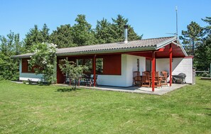 En liten, envåningsbyggnad med en täckt uteplats, en skorsten och en satellantenn.