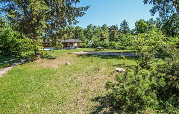 En park med en plats för picknick, en liten paviljong och en damm.