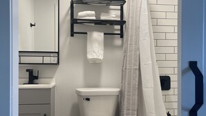 Une salle de bain moderne équipée de toilettes, d’un lavabo, d’un porte-serviettes et d’un rideau de douche.