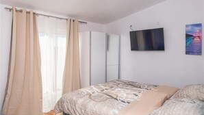 A bedroom with a bed, a wardrobe, a TV, and a painting on the wall.