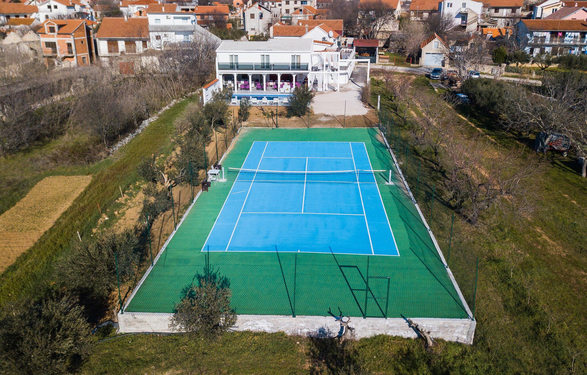 Luftaufnahme eines Tennisplatzes, umgeben von Wohnhäusern.