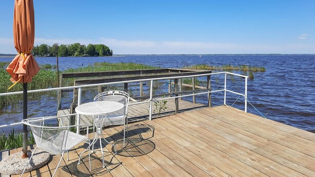 A wooden deck with outdoor seating, a railing, and a view of a lake.