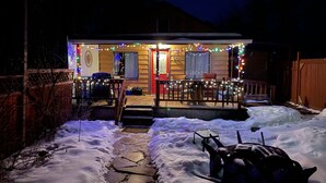 Una casa con un sendero cubierto de nieve que lleva a un porche decorado con luces de cadena.