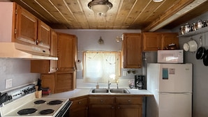 Una cocina compacta con armarios de madera, una estufa blanca, un fregadero y un refrigerador.