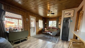Interior acogedor de una cabaña con techo de madera, un sofá con cojines estampados, una mesa de comedor y una zona de bar.