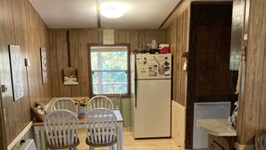 A compact kitchen with wooden walls and a central island. There is a refrigerator, a sink, and a window providing natural light. - 3 BR Cabin in Bankhead Forest of North Alabama (Moulton)
