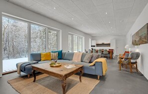Ein geräumiges Wohnzimmer mit einem großen Sofa, einem Holztisch und einem Essbereich im Hintergrund.