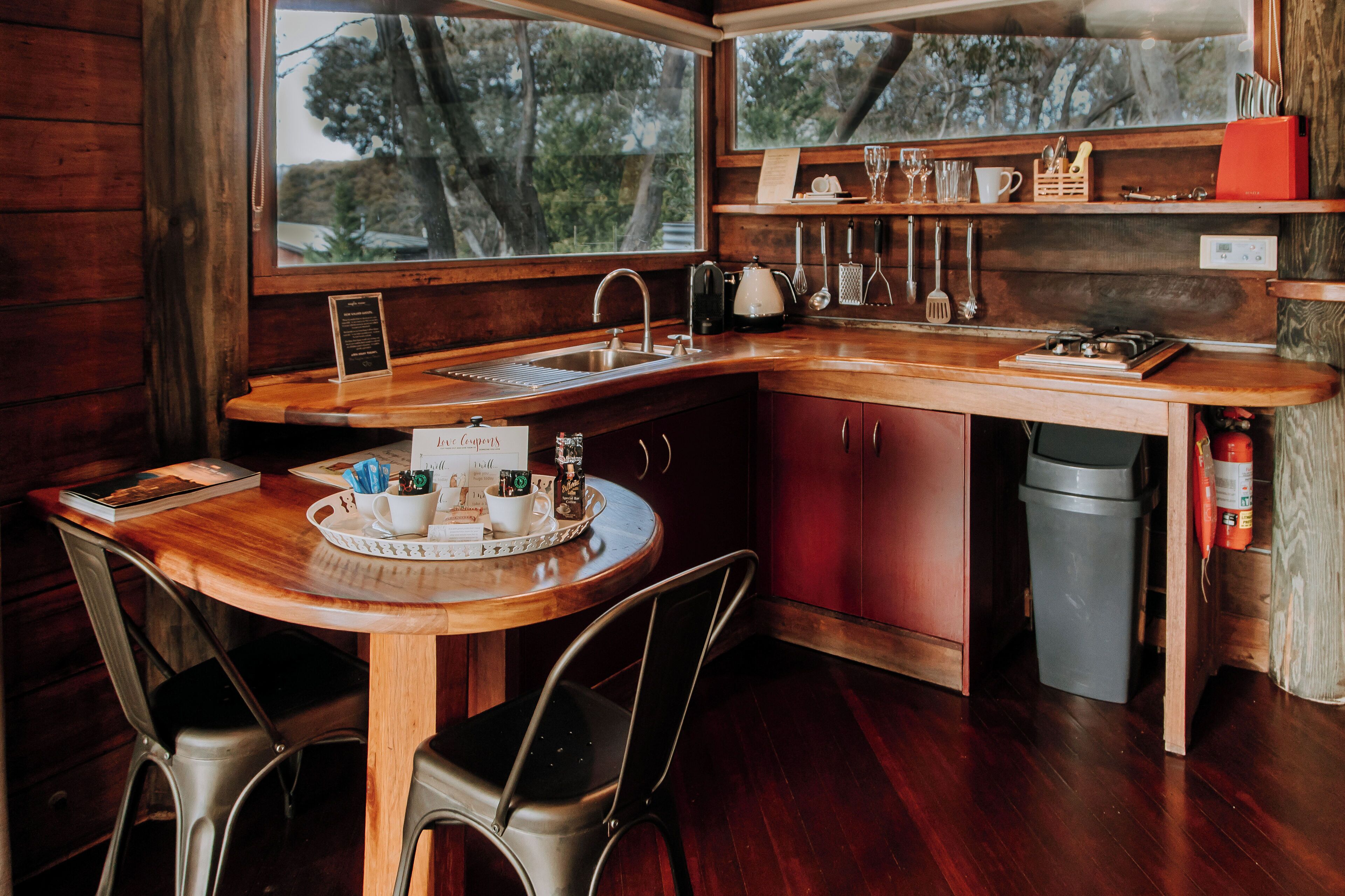 A cozy kitchen with wooden countertops, a sink, and a window overlooking trees.