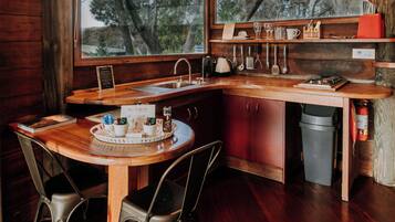 A cozy kitchen with wooden countertops, a sink, and a window overlooking trees.