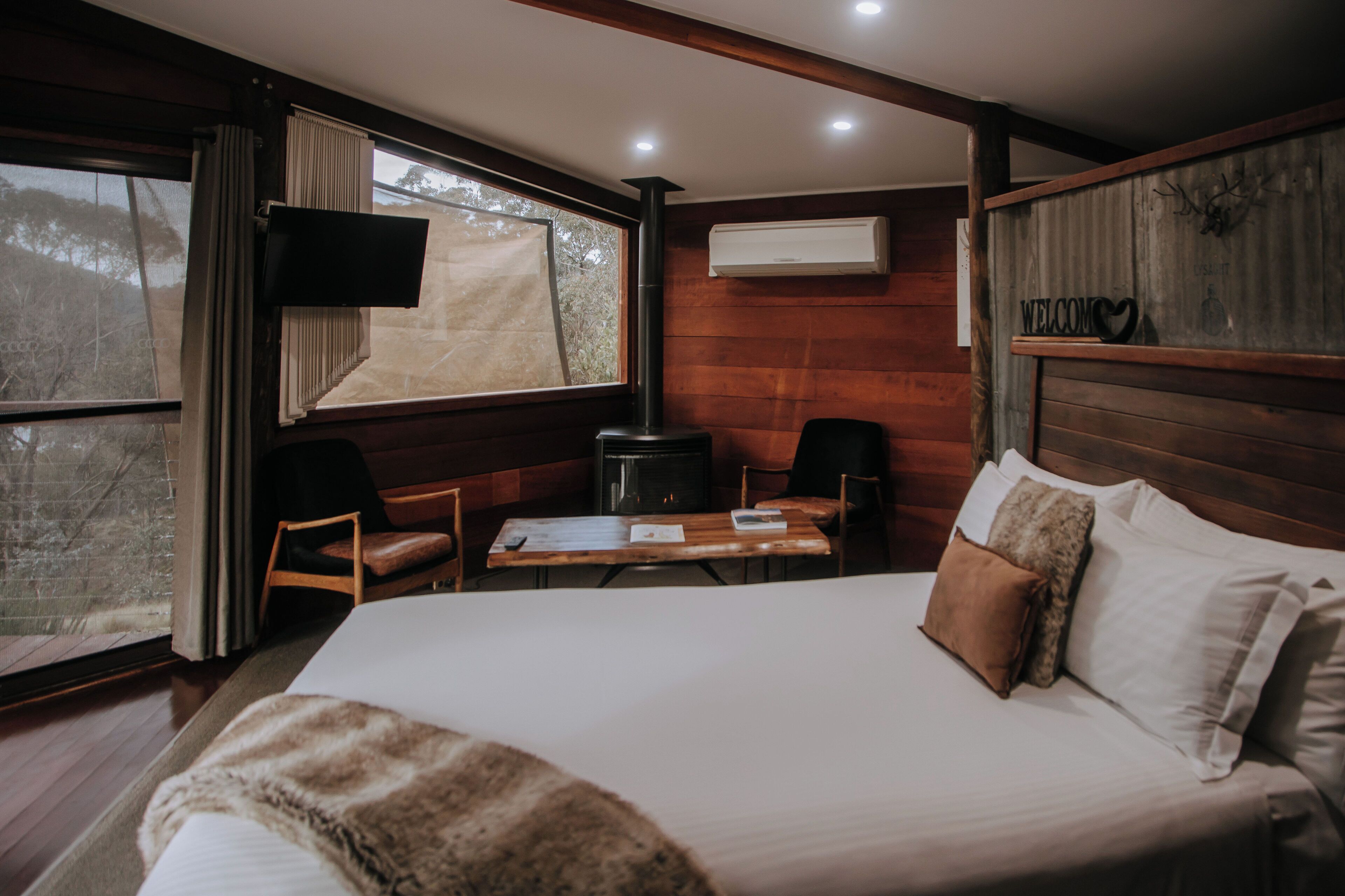 A cozy room with a bed, a table, chairs, a TV, and a fireplace.