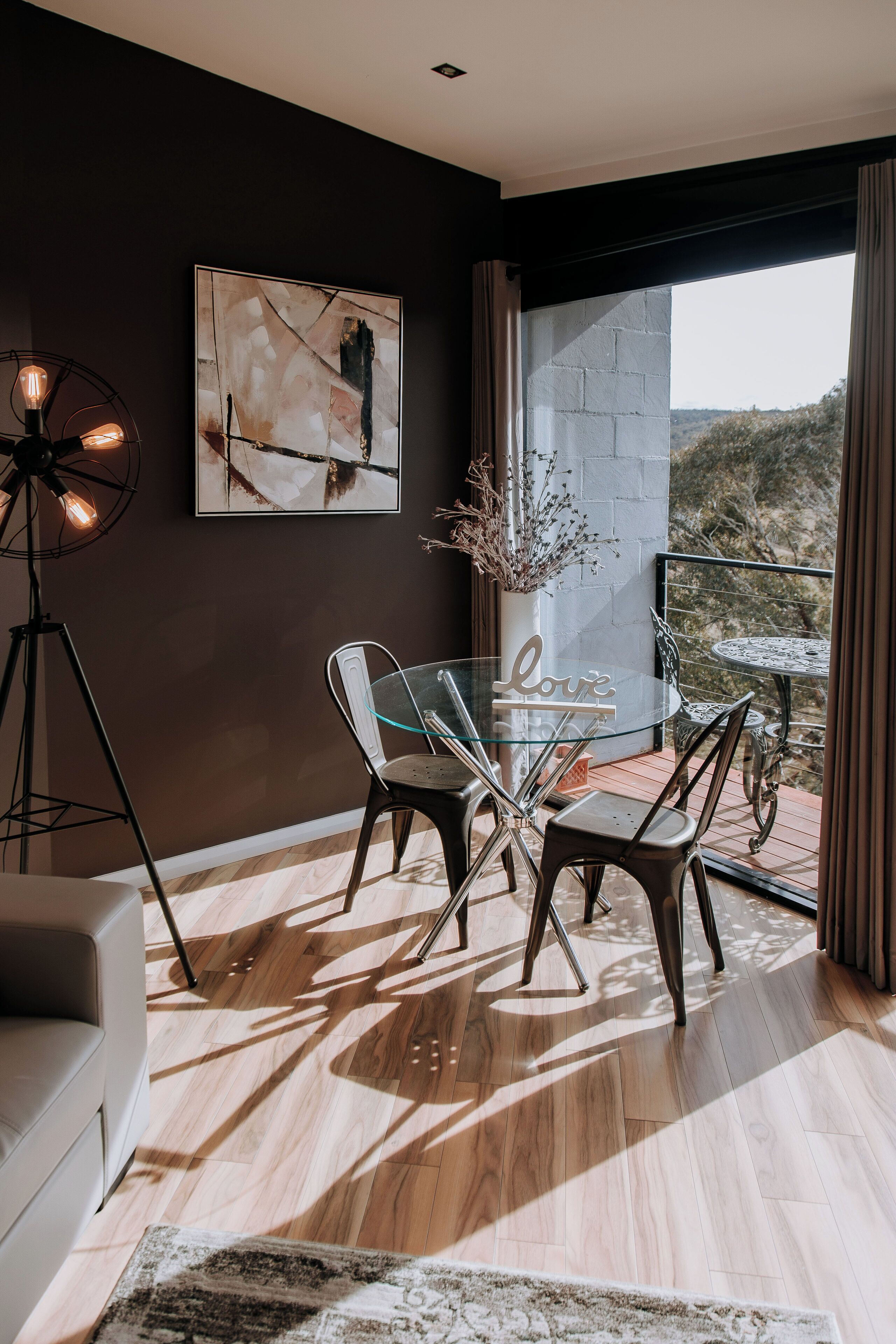 Un espace repas moderne avec une table en verre, des chaises en métal et une vue sur l’extérieur.