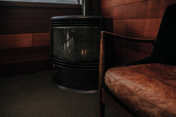 A corner room with a wood-paneled wall, a black heater, and a leather chair.